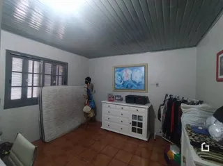 Quarto com paredes brancas e janelas com moldura de madeira.