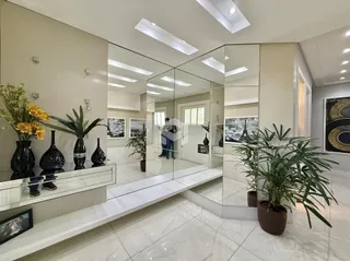 Hall de entrada com espelhos e piso de mármore claro.