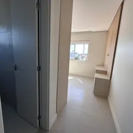 Corredor interno com paredes claras e porta branca.