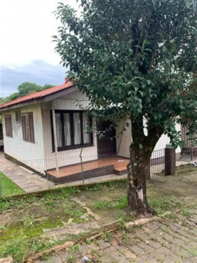 Fachada de uma casa residencial em Lajeado, Brasil, parcialmente coberta por uma árvore.