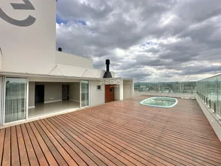 Vista da fachada de uma residência com deck de madeira e piscina.