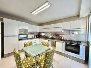 Vista da cozinha e sala de jantar com armários brancos.