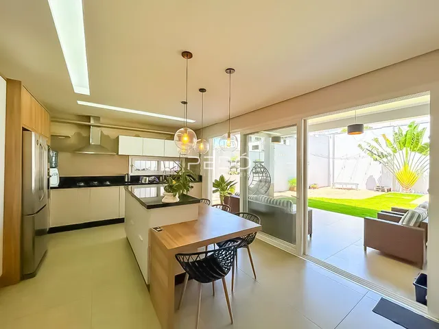 Vista de uma cozinha moderna com sala de jantar e portas de vidro que dão para um jardim.
