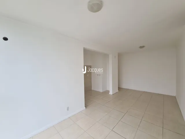 Interior de uma sala com paredes brancas e piso de cerâmica.