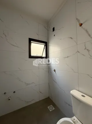 Interior de um banheiro com paredes brancas e detalhes em mármore claro.