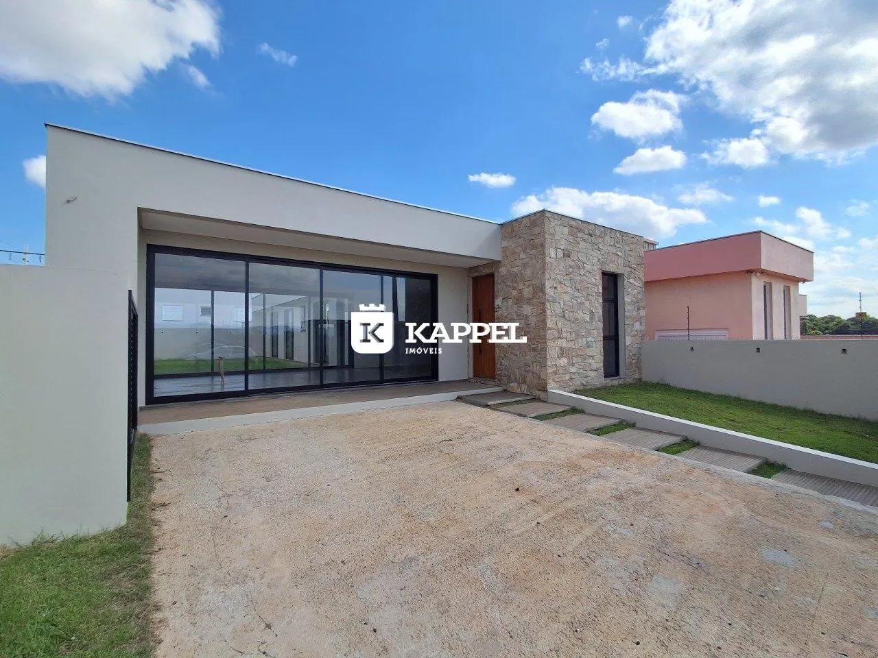 Fachada moderna de uma residência com grandes painéis de vidro e área externa.
