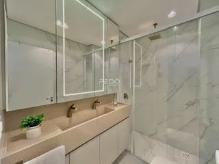 Banheiro com revestimento em mármore e box de vidro.