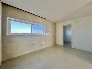 Interior de uma sala com grande janela e piso claro.