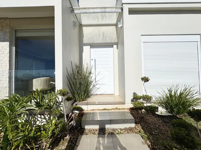 A fachada da residência em Lajeado exibe paredes brancas e um jardim frontal bem cuidado.