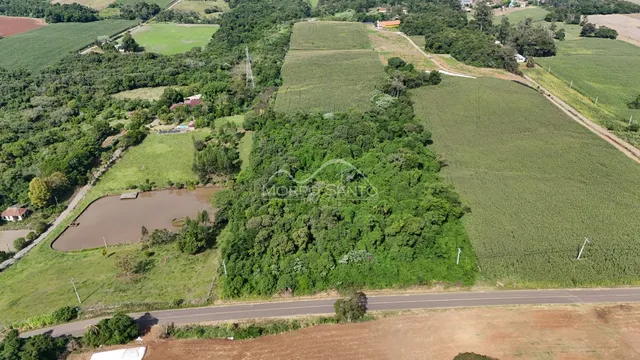 Vista aérea de uma propriedade rural com campos agrícolas e vegetação densa.