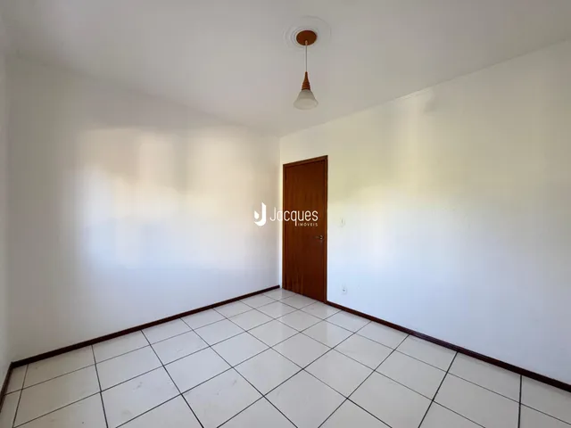 Hall com piso de cerâmica branca e porta de madeira.