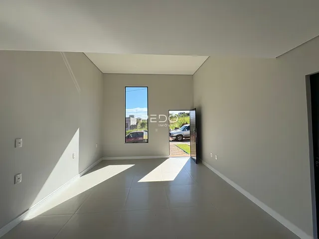 Ambiente interno de uma sala com piso claro e paredes brancas.