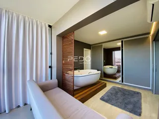 Sala de estar com cortinas brancas e ambiente de transição para um banheiro.