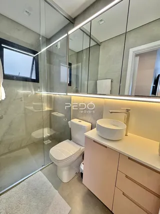 Interior de um banheiro moderno com box de vidro e louças brancas.