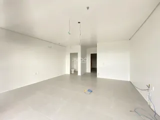 Interior de um espaço amplo e vazio com paredes brancas e piso claro.