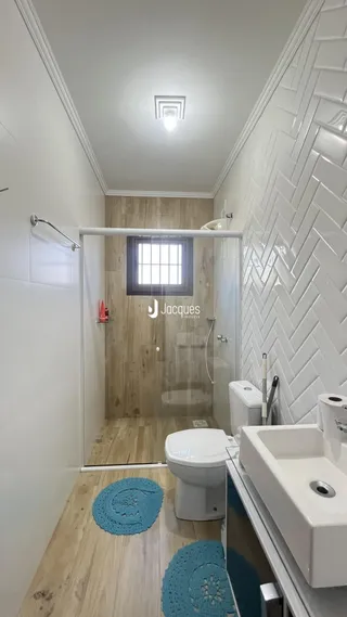 Um banheiro com box de vidro e piso de madeira.