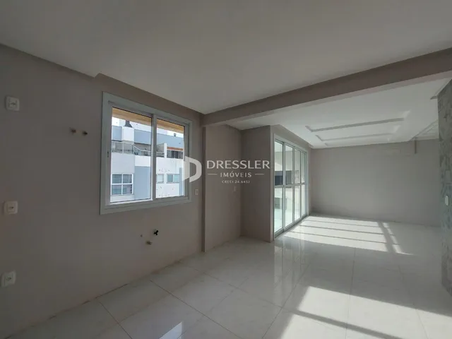 Interior de uma sala de estar com grandes janelas e piso claro.