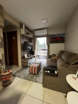Sala de estar com sofá e televisão em um apartamento no Brasil.