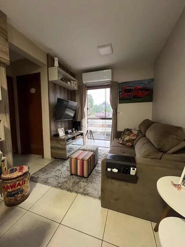 Sala de estar com sofá e televisão em um apartamento no Brasil.