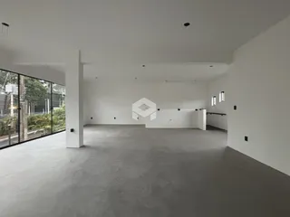 Espaço interno amplo com paredes brancas e piso cinza claro.