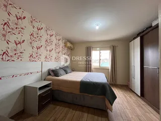 Quarto com parede floral e cabeceira de madeira no imóvel em Lajeado.