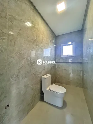 Banheiro com paredes de mármore e vaso sanitário branco.