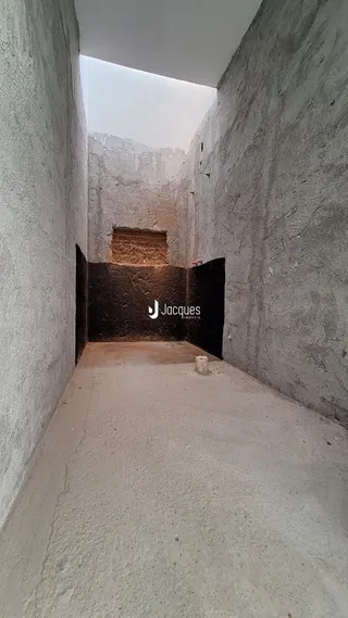 Corredor interno com paredes de concreto aparente.