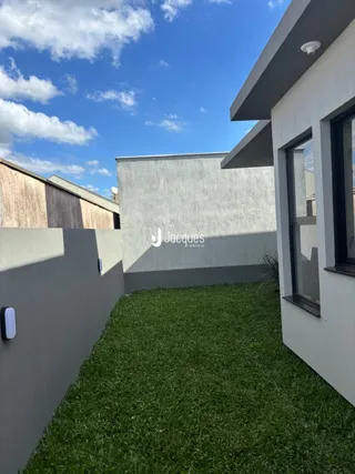 Fachada de uma residência em Lajeado, Brasil, mostrando uma parede branca e um gramado verde.