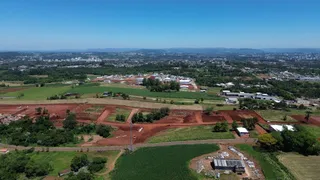 Vista aérea de terras agrícolas e áreas verdes com uma cidade ao fundo.