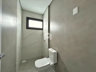 Interior de um banheiro com paredes em tom neutro e piso claro.