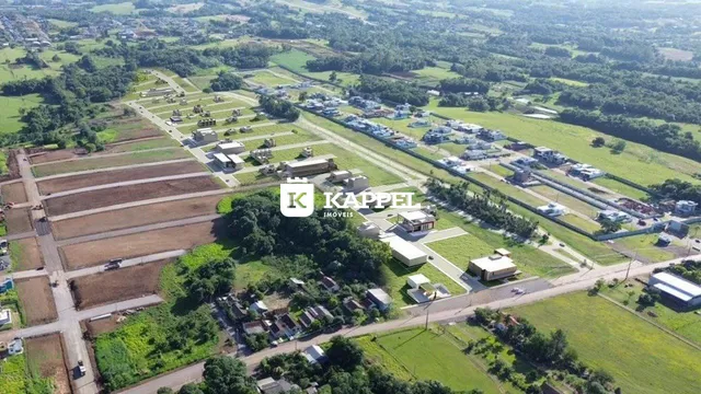 Vista aérea de um loteamento com áreas verdes e campos agrícolas.