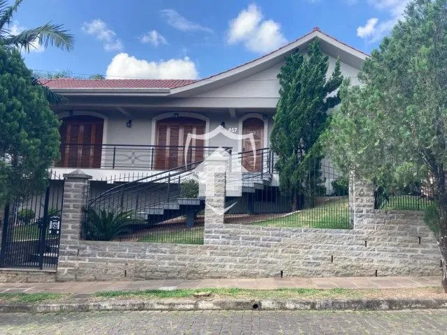 Fachada de uma residência com muro de pedra e portão de ferro.