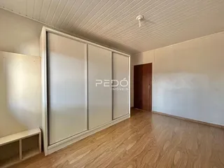 Quarto com armário embutido e piso de madeira clara.