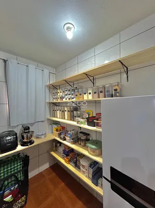 Vista interna de uma cozinha com prateleiras de madeira e armários brancos.