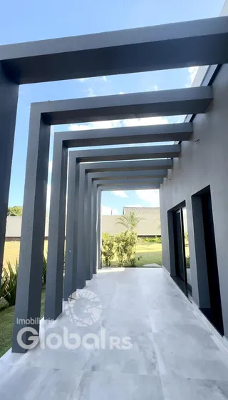 Corredor longo com estrutura de concreto e vigas em uma residência.