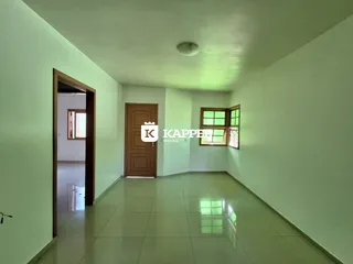 Hall de entrada com paredes brancas e piso de cerâmica claro.