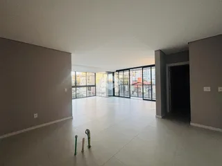 Sala ampla com piso de cerâmica e grandes janelas de vidro.