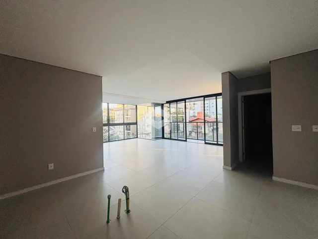 Sala ampla com piso de cerâmica e grandes janelas de vidro.