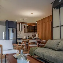 Sala de estar com sofá e área de cozinha visível em um imóvel.