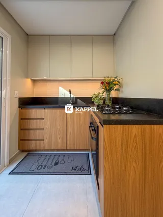 Vista interna de uma cozinha com armários de madeira e bancadas escuras.