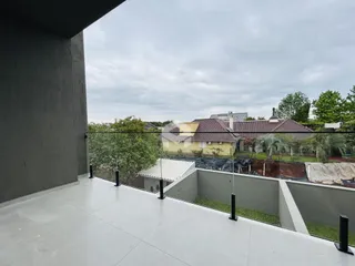Vista de uma varanda com piso de concreto e grade de vidro.