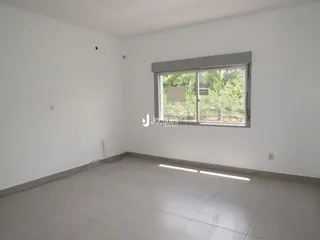 Foto de um ambiente interno vazio com paredes brancas e piso claro.