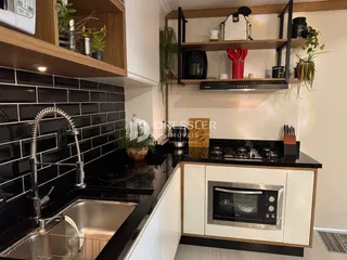 Cozinha moderna com armários brancos e bancadas pretas.