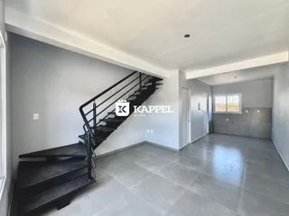 Hall de entrada com escadas pretas e piso de cerâmica clara.