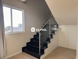 Ambiente interno mostrando uma sala com janela e escadaria moderna.