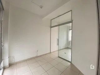 Interior de um corredor com piso de cerâmica clara e paredes brancas.