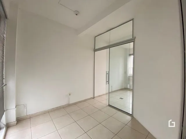 Interior de um corredor com piso de cerâmica clara e paredes brancas.