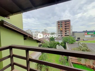 Uma vista da varanda mostrando vegetação e edifícios ao fundo.