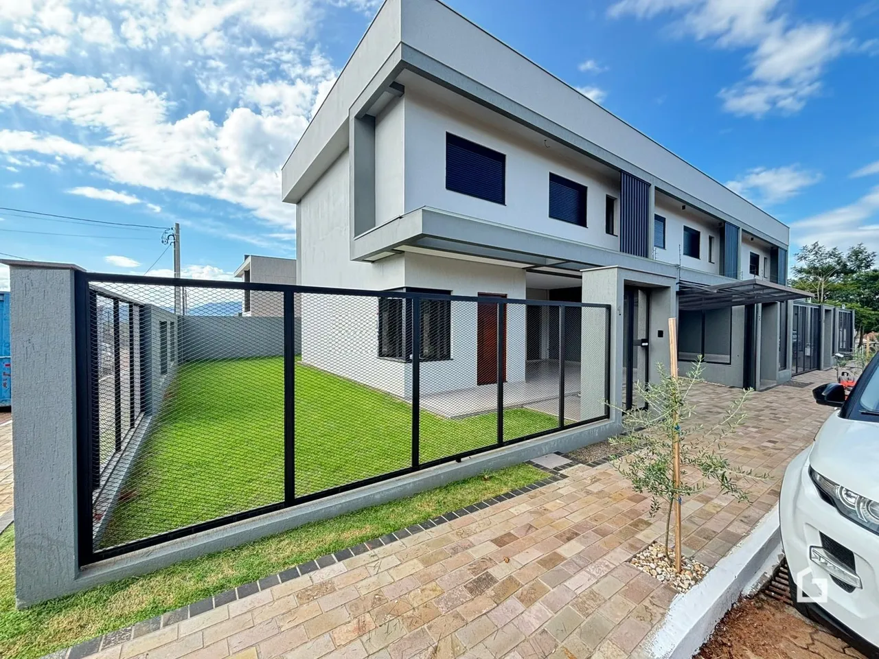 Fachada de uma casa moderna em Lajeado, Brasil, com quintal gramado e cerca.
