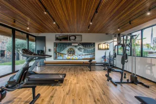 Ambiente interno amplo com piso de madeira e equipamentos de ginástica.